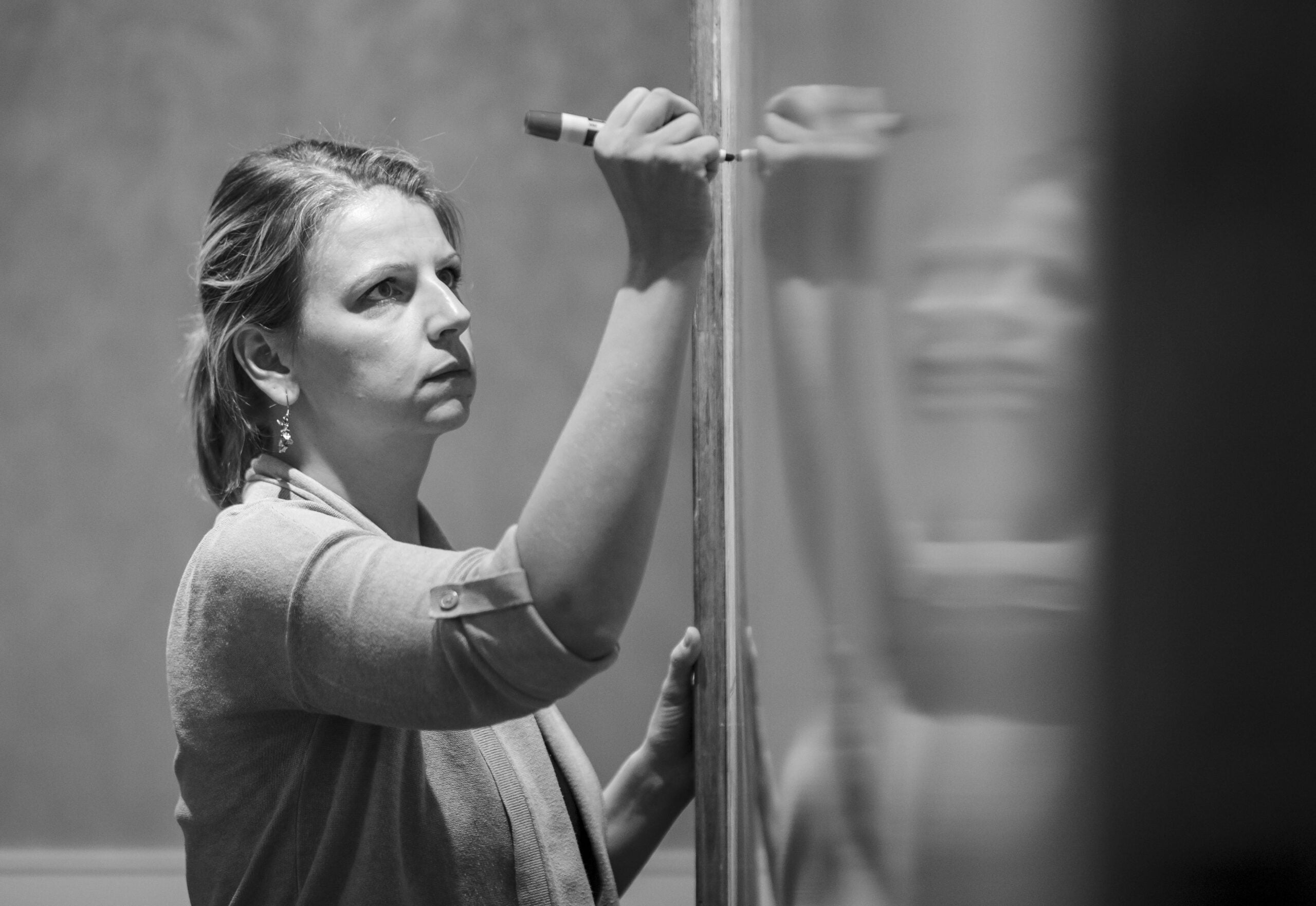 Serious Fellow writes on dry erase board.