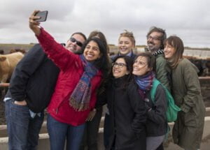 Hip young leaders pose for a selfie in front of cattle